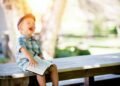 boy sitting on bench while holding a book