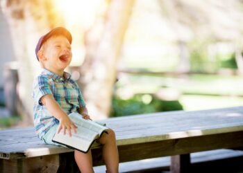 boy sitting on bench while holding a book